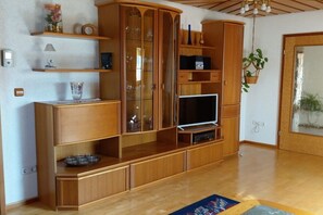 Ein Holz-Multifunktionsmöbel mit Fernseher, Regalen und Schranken mit Glastüren.
