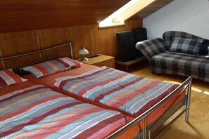 Ein Zimmer mit zwei Betten, einer Couch, einem Fernseher und einer Lampe.