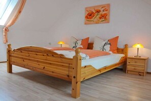 A wooden bed with a headboard, a bedside table with a lamp, and a wall-mounted painting. - Holiday apartment in the Harz Mountains with 2 bedrooms (Bad Harzburg)