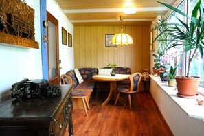 A cozy dining area with a wooden table and bench seating, surrounded by potted plants and a vintage radio. - Holiday apartment in the Harz Mountains with 2 bedrooms (Bad Harzburg)