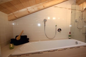 Ein Badezimmer mit einer Badewanne, einer Dusche und einem Duschbereich mit Glaswand.