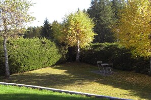 A well-maintained garden with a lawn, a tree, and a metal table and chairs. - "Sunshine" in Lenzkirch (Lenzkirch)