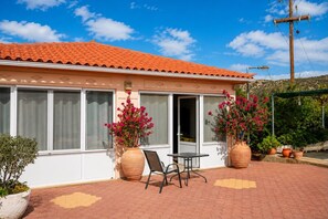 A building with a tiled roof, large windows, and a patio area with a table and chairs.