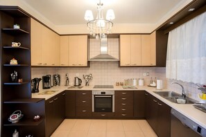 A modern kitchen with dark brown cabinets, a central island, a built-in oven, and a stainless steel sink. - Holiday Home 'Anastasia's Olive Grove' with Mountain View, Wi-Fi and Air Conditioning (Γούβες)