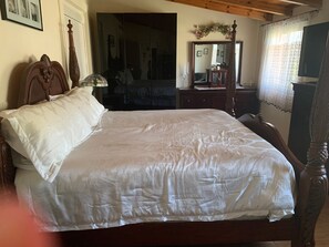 A bedroom with a large bed, wooden headboard, a dresser, a mirror, and a window with curtains. - Holiday Home 'Anastasia's Olive Grove' with Mountain View, Wi-Fi and Air Conditioning (Γούβες)