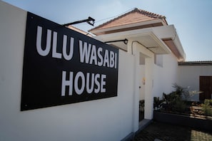 Un letrero que dice 'ULU WASABI HOUSE', mostrando claramente la entrada y un techo de tejas.