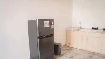 Una cocina compacta con refrigerador de acero inoxidable, un lavamanos y armarios de madera.