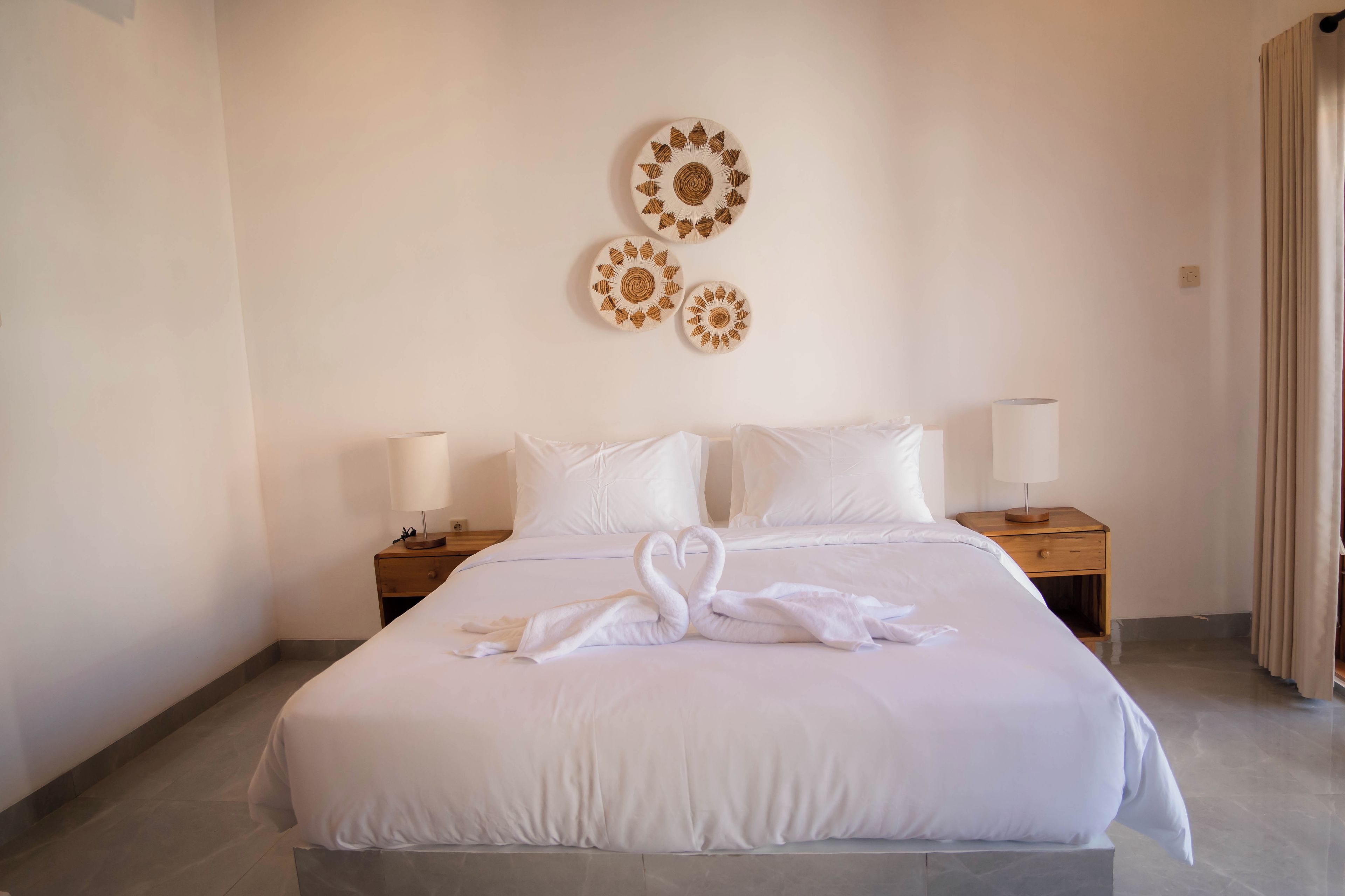 Habitación de hotel con una cama grande, dos mesitas de noche con lámparas y decoración en la pared.