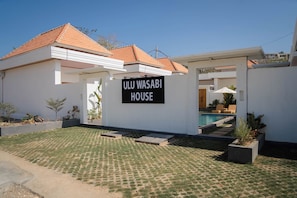A modern house with a sign reading 'ULU WASABI HOUSE' and a swimming pool in the background.
