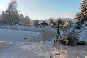 A snowy landscape with a wooden structure, a small tree, and a snow-covered ground. - Holiday apartment with 1 bedroom (Rieden am Forggensee)