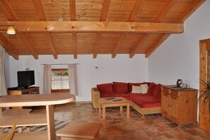 Sostre de fusta, un sofà vermell, una televisió i una taula de vimet a una habitació.