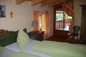 A room with a bed, a chair, a lamp, and a window with curtains. - Holiday apartment with 1 bedroom (Rieden am Forggensee)