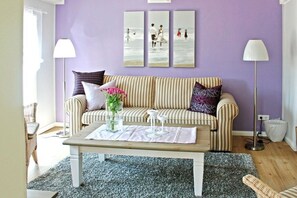 A living room with a striped sofa, a coffee table, and a wall with three framed pictures. - Holiday home in Uphusum with swimming pool (Uphusum)