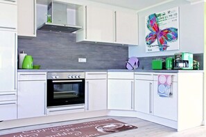 A modern kitchen with white cabinets, a built-in oven, and a coffee machine. - Holiday home in Uphusum with swimming pool (Uphusum)