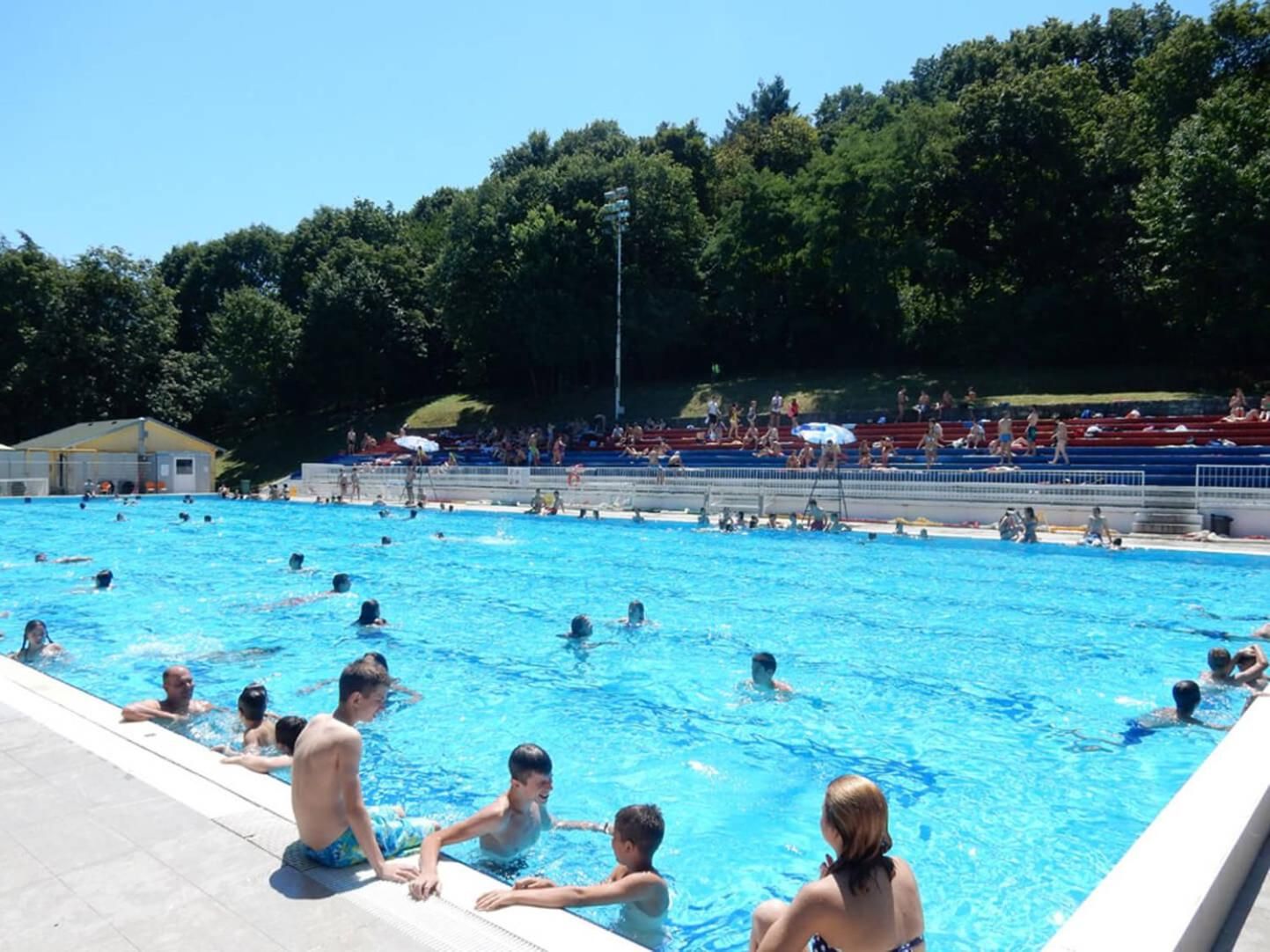 A swimming pool with multiple lanes and people swimming and playing.