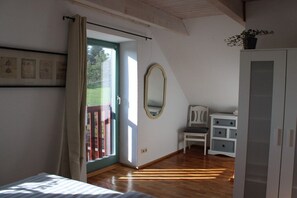 A bedroom with a bed, a chair, a dresser, a mirror, and a door leading to an outdoor area. - Holiday home Harz with heart 4 (Braunlage OT Hohegeiß)