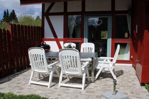 An outdoor patio with a table and four chairs, a kettle, and a flower arrangement. - Holiday home Harz with heart 4 (Braunlage OT Hohegeiß)