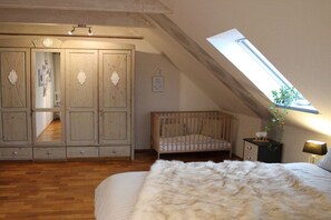 Une chambre avec un plafond en pente, un berceau, une armoire et un puits de lumière.