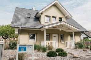 A two-story house with a covered front porch, a satellite dish, and a sign indicating a design competition. - Holiday home with 1 bedroom (Maasholm-Bad)
