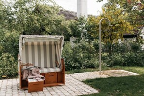 A garden with a wooden bench and a metal shower structure. - Holiday home with 1 bedroom (Maasholm-Bad)