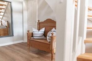 A wooden bed with a headboard, two pillows, and a bench. - Holiday home with 1 bedroom (Maasholm-Bad)