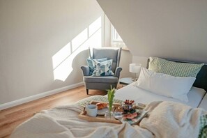 A cozy bedroom with a bed, a chair, and a breakfast tray. - Holiday home with 1 bedroom (Maasholm-Bad)