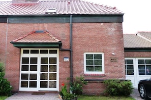 A brick building with a tiled roof, a large garage door, and a small window. - Holiday home in Borkum with swimming pool (Borkum)