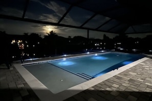 An outdoor swimming pool with a clear view of the surrounding area, including distant buildings and a night sky. - Villa in Cape Coral with swimming pool (Cape Coral)