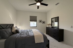 A bedroom with a bed, dresser, ceiling fan, and window. - Villa in Cape Coral with swimming pool (Cape Coral)