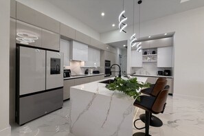 A modern kitchen with a central island, stainless steel appliances, and pendant lighting. - Villa in Cape Coral with swimming pool (Cape Coral)
