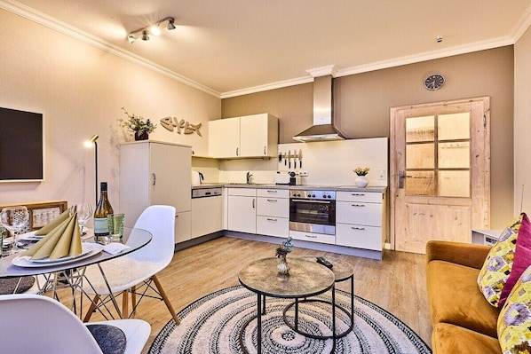 A compact living space with a dining area, kitchenette, and a cozy seating area. - Holiday apartment with 1 bedroom (Westerland)