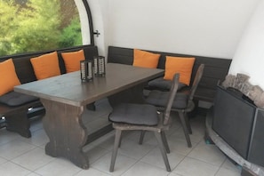 A dining area with a dark wooden table, matching chairs, and orange cushions. - Alpine Jewel Garmisch (Garmisch-Partenkirchen)