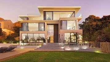 Une maison moderne à deux étages, dotée de grandes fenêtres, d’un toit plat et d’une pelouse bien entretenue.