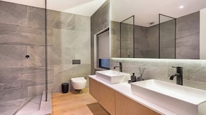 Een moderne badkamer met een grote spiegel, twee wasbakken en een douchecabine.
