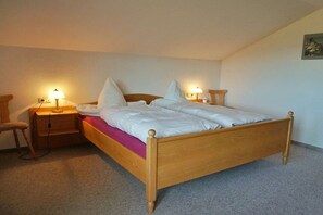 Ein Einzelbett mit Holzrahmen, zwei Nachttische mit Lampen und ein Sessel.