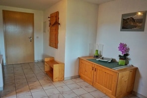 Ein Zimmer mit einem Holzkabinett, einer Tür und einem Wandregal.