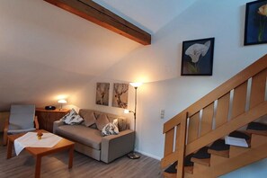 A living room with a sofa, a coffee table, a lamp, and a staircase. - House at Gutach No. 10 (Titisee-Neustadt)