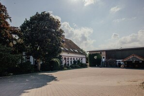 Ein Gebäude mit einem gepflasterten Innenhof, einem großen Baum und einem stallähnlichen Gebäude.
