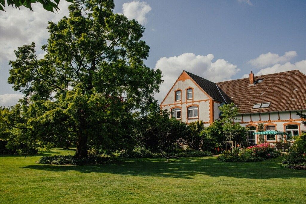 A large house with a sloped roof, surrounded by a well-maintained lawn and trees.