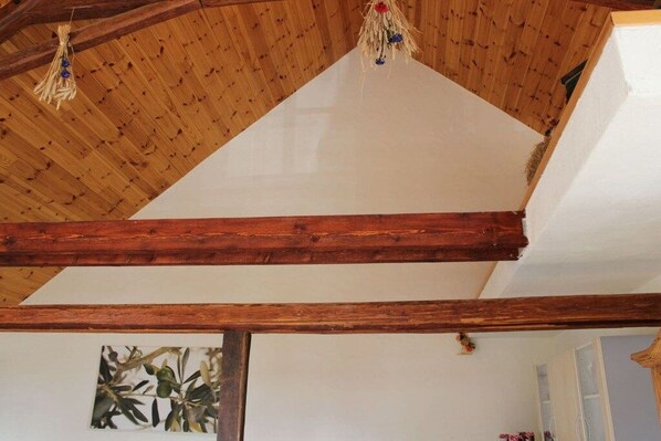 A room with a sloped wooden ceiling, exposed beams, and a white wall with a framed picture. - Holiday apartment for families, room (Treis-Karden)