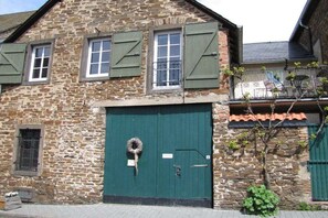 A stone building with a green door, windows with shutters, and a small tree in front. - Holiday apartment for families, room (Treis-Karden)