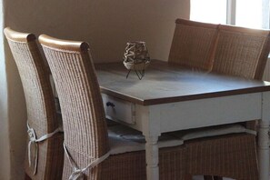 A dining table with wicker chairs and a woven stool. - Holiday apartment for families, room (Treis-Karden)