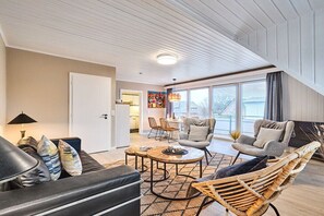 A modern living room with a sofa, chairs, a coffee table, and a dining area visible through an open door. - Holiday apartment in Sylt with 2 bedrooms (Westerland)