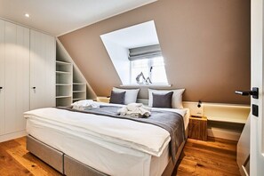 A bedroom with a large bed, a skylight, a built-in wardrobe, and a small bedside table. - Holiday home with 1 bedroom (Westerland)
