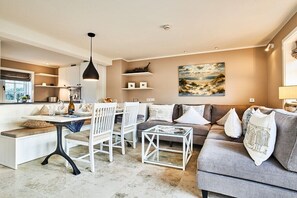 A modern living room with a sofa, chairs, a coffee table, and a dining area with a bench. - Holiday home with 1 bedroom (Westerland)