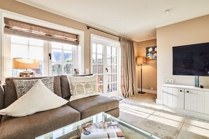 A living room with a sofa, a glass coffee table, a television, and a cabinet. - Holiday home with 1 bedroom (Westerland)