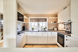 A modern kitchen with white cabinetry, a black countertop, and a window with a view. - Holiday home with 1 bedroom (Westerland)