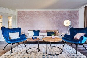 A living room with a sofa, two armchairs, a coffee table, and a lamp. - Holiday apartment in Sylt with 3 bedrooms (Westerland)