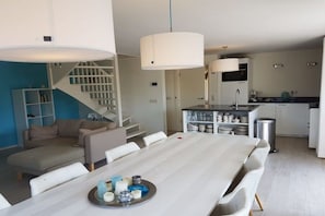 Ein modernes Interieur mit Essbereich, Küche und Treppe.