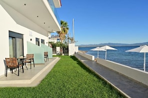A hotel balcony with a view of the sea, outdoor seating, and a well-maintained lawn. - Vista Paraiso Inn (Nea Potidea)